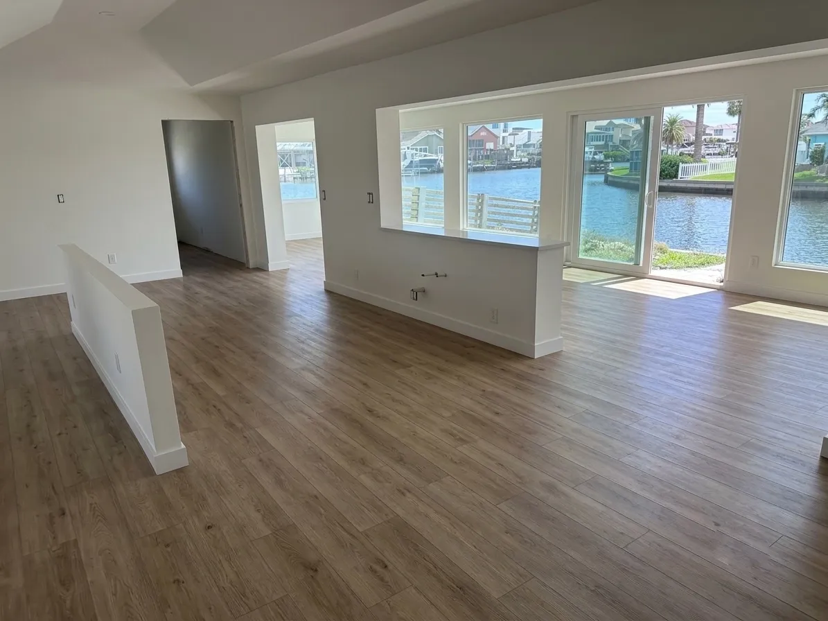 The same waterfront living area finished, with light oak-look laminate throughout and the canal visible through the sliding doors