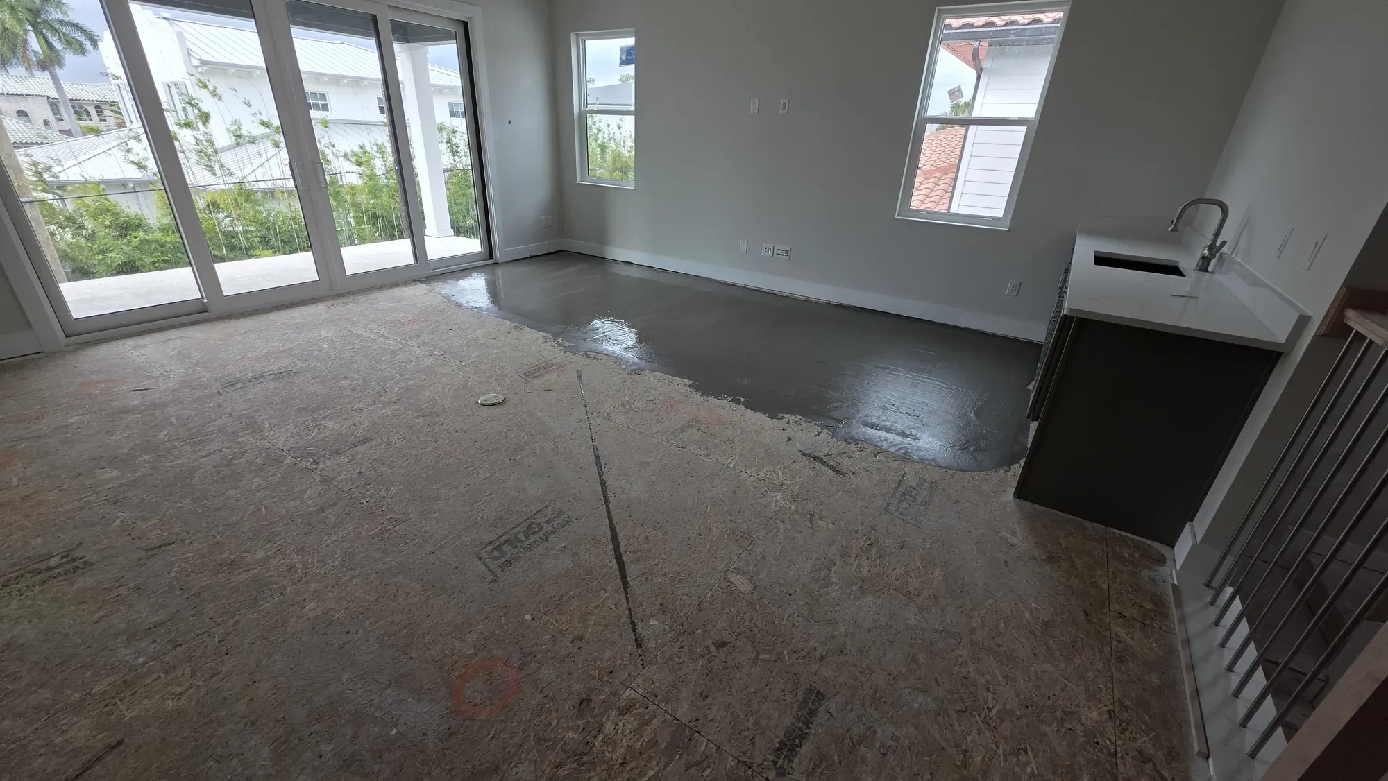 Open living area in Seffner with bare OSB subfloor and freshly applied leveling compound, before installation
