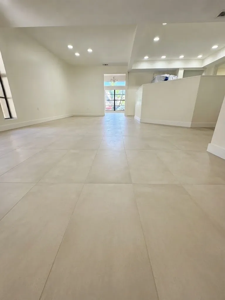 The same living area finished, with pale large-format tile running the length of the room to the window at the far end