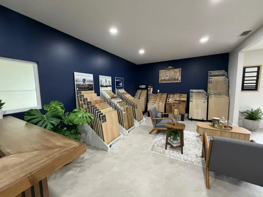 Rows of flooring sample boards standing on white display stands along the navy wall of the showroom, with the seating area at the back