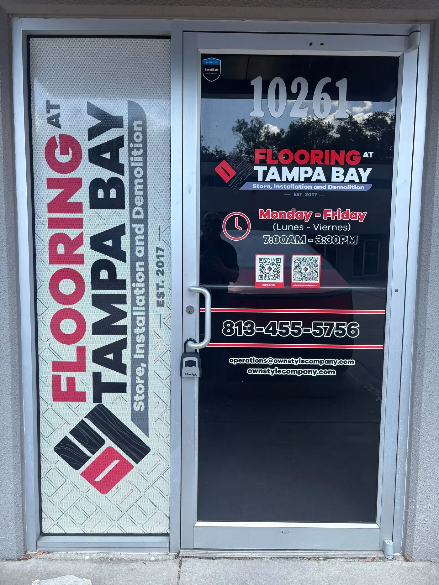 The showroom entrance at 10261 Windhorst Rd: a glass door with the Flooring at Tampa Bay logo, the street number, the Monday to Friday hours and the phone number printed on it